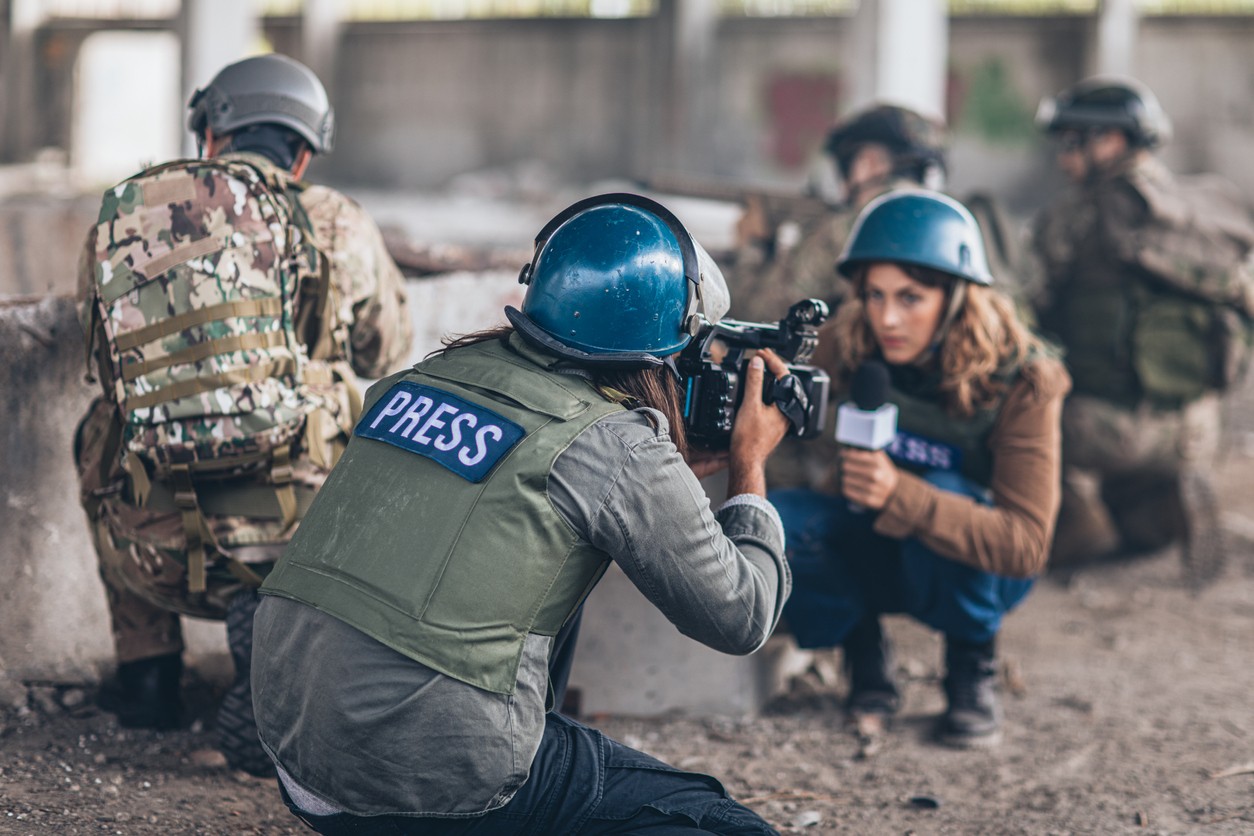 Reporter de guerre en zone hostile s'adressant à la caméra